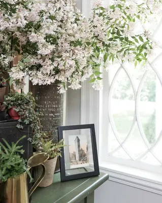 a picture frame on a table next to a window with flowers at Granville House in Great Barrington