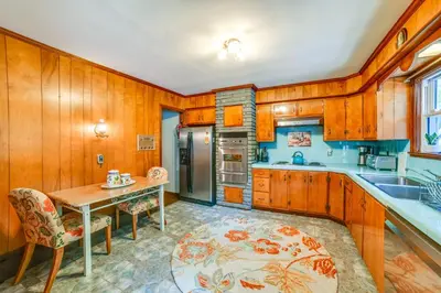 a kitchen with wooden cabinets and a table and chairs at Serene Home with On-Site Brook in Callicoon Center in Callicoon Center