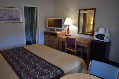 a hotel room with a bed and a desk with a television at POCONO NIGHT LODGE in Bartonsville