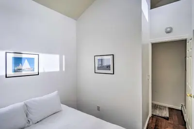a white bedroom with a bed and two pictures on the wall at The Mountain House Windham Retreat with Hot Tub! in Windham