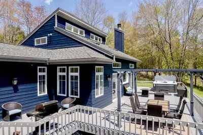 a blue house with a deck and a grill at The Mountain House Windham Retreat with Hot Tub! in Windham