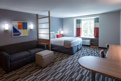 a hotel room with a bed and a couch and a table at Microtel Inn & Suites by Wyndham Amsterdam NY in Amsterdam