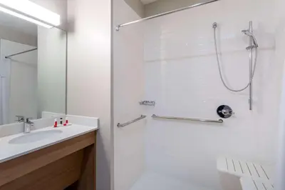 a white bathroom with a shower and a sink at Microtel Inn & Suites by Wyndham Amsterdam NY in Amsterdam