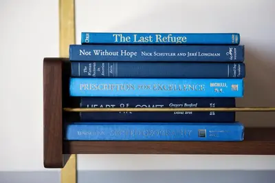 a stack of books sitting on a shelf at The Hoxton, Williamsburg in Brooklyn