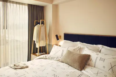 a bedroom with a bed with white sheets and a window at The Hoxton, Williamsburg in Brooklyn