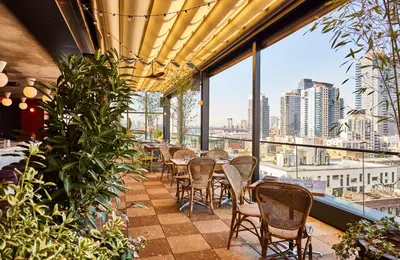 a restaurant with tables and chairs and a view of the city at The Hoxton, Williamsburg in Brooklyn