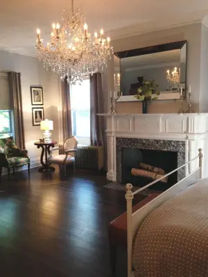 a living room with a fireplace and a chandelier at Gardner Farm Inn in Troy