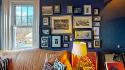 a living room with a couch and a wall of pictures at Gardner Farm Inn in Troy