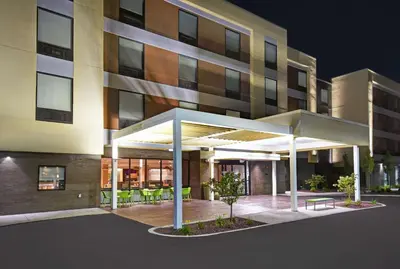 a building with a covered patio in front of it at Home2 Suites By Hilton Utica, Ny in Utica