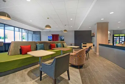 a room with a couch with tables and chairs at Home2 Suites By Hilton Utica, Ny in Utica