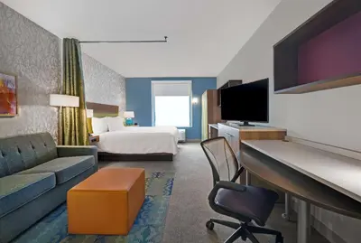 a hotel room with a bed and a couch and a tv at Home2 Suites By Hilton Utica, Ny in Utica
