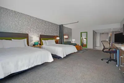 a hotel room with two beds and a television at Home2 Suites By Hilton Utica, Ny in Utica