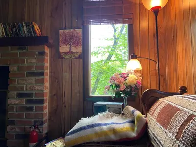 a bedroom with a bed and a window and a vase of flowers at Saw Creek Cabin - Regent Hilltop in Bushkill