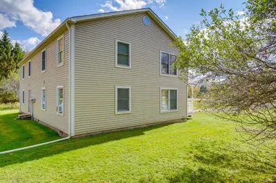 a large white house with a grass yard at Peaceful Catskills Condo with Deck and Mountain View! in Windham