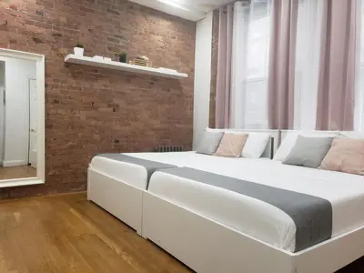 a large white bed in a room with a brick wall at Hotel and the City, Empire State Building in New York