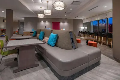 a couch in a room with tables and chairs at Home2 Suites By Hilton Wayne, NJ in Wayne