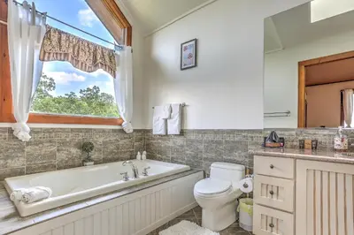 a bathroom with a tub and a toilet and a window at Peaceful Mountian Oasis Firepit, Hot Tub, Sauna! in Vernon Township