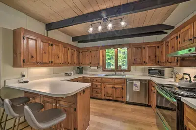 a kitchen with wooden cabinets and a large white island at Sleek Cabin with Deck, 8 Miles to Mount Snow and Hikes in Wilmington