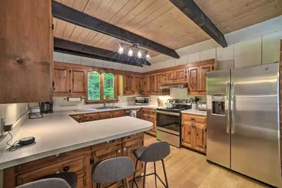 a kitchen with wooden cabinets and a stainless steel refrigerator at Sleek Cabin with Deck, 8 Miles to Mount Snow and Hikes in Wilmington