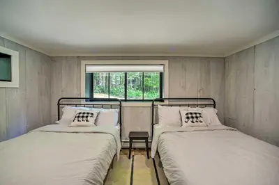 two beds in a small room with a window at Sleek Cabin with Deck, 8 Miles to Mount Snow and Hikes in Wilmington