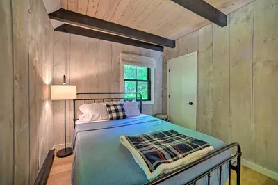 a bedroom with a bed in a room with wooden walls at Sleek Cabin with Deck, 8 Miles to Mount Snow and Hikes in Wilmington