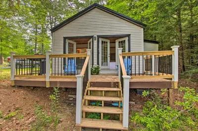 a tiny house with a large porch and wooden stairs at East Otis Vacation Rental with Private Deck and BBQ! in East Otis