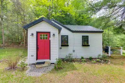 a small shed with a red door in a yard at East Otis Vacation Rental with Private Deck and BBQ! in East Otis