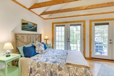 a bedroom with a bed and two windows at East Otis Vacation Rental with Private Deck and BBQ! in East Otis