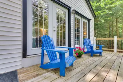 two blue adirondack chairs on the porch of a house at East Otis Vacation Rental with Private Deck and BBQ! in East Otis