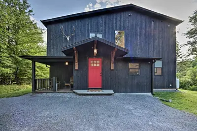 a black house with a red door on a gravel driveway at Luxury Home with Deck Explore the Catskill Mtns! in Windham