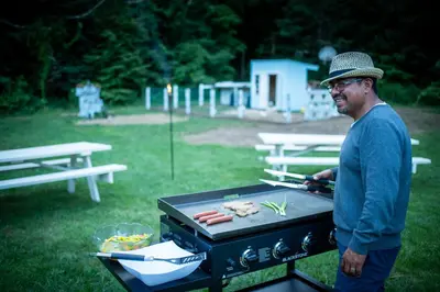 a man standing next to a grill with meat and vegetables at Arcady Mountain Motor Lodge in Sunderland