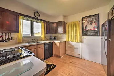 a kitchen with wooden cabinets and a white refrigerator at Albany Home with Fenced Yard and Patio - Pets Welcome! in Albany
