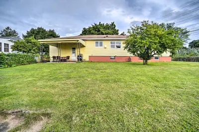 a yellow house with a tree in a yard at Albany Home with Fenced Yard and Patio - Pets Welcome! in Albany
