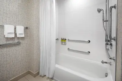 a bathroom with a white tub and a shower at Holiday Inn Express & Suites Woodside LaGuardia Airport in Queens