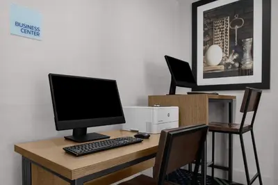 a desk with a computer monitor and a keyboard at Holiday Inn Express & Suites Woodside LaGuardia Airport in Queens