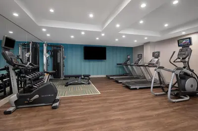 a gym with several tread machines and a flat screen tv at Holiday Inn Express & Suites Woodside LaGuardia Airport in Queens