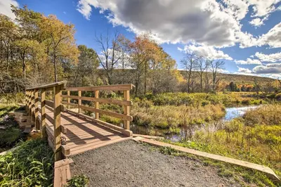 a wooden bridge over a river in a field at Spacious Apt with Yard 3 Mi to Windham Mountain in Windham
