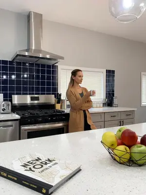 a woman standing in a kitchen with a bowl of fruit at Holly Lodge - Ski Windham Hunter Catskills in Prattsville