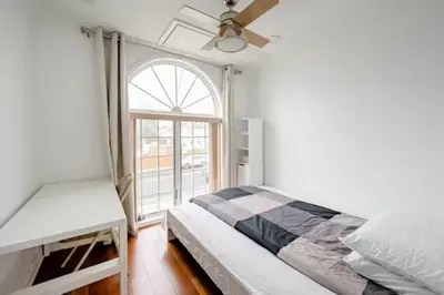 a bedroom with a bed with a ceiling fan and a window at Luxury Hotel-Style Room in Queens, New York in Bayside