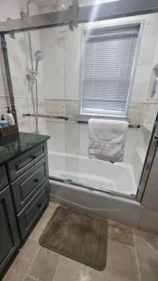 a bathroom with a shower and a tub with a towel at Luxury Hotel-Style Room in Queens, New York in Bayside