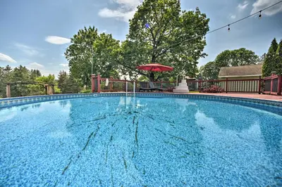 a large blue swimming pool with a red umbrella at Stylish Suburban Getaway, 10 Miles to Royal Mtn! in Johnstown