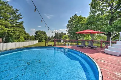 a swimming pool on a deck with an umbrella at Stylish Suburban Getaway, 10 Miles to Royal Mtn! in Johnstown