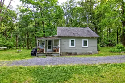 a small house in the middle of a field at Camelback cottage - on ONE ACRE & near local attractions in Tannersville