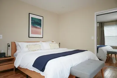 a white bedroom with a large bed with a blue blanket at Chateau Lodge - Ski Shandaken, Hunter, Catskills, Windham, Belleayre in Shandaken