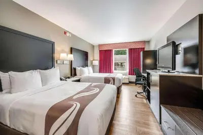 a hotel room with two beds and a flat screen tv at Quality Inn Poughkeepsie in Poughkeepsie