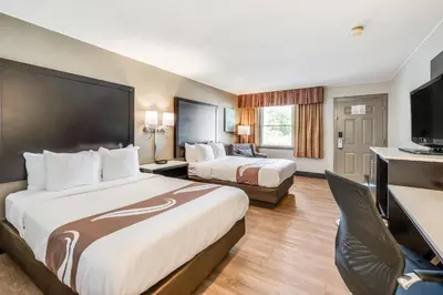 a hotel room with two beds and a desk at Quality Inn Poughkeepsie in Poughkeepsie
