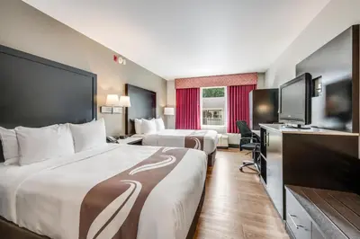 a hotel room with two beds and a flat screen tv at Quality Inn Poughkeepsie in Poughkeepsie