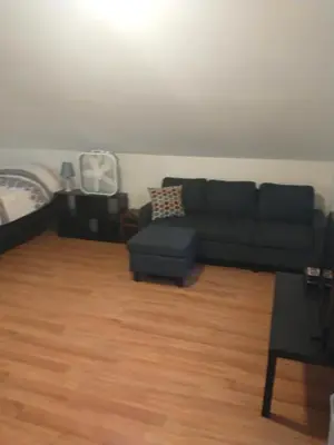 a living room with a black couch and a wooden floor at Two Brooks Lodge in Bennington