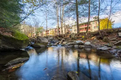 a river with rocks and buildings in the background at Holiday Inn Club Vacations Oak n Spruce Resort in the Berkshires in South Lee