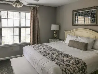 a bedroom with a large bed and two windows at Holiday Inn Club Vacations Oak n Spruce Resort in the Berkshires in South Lee